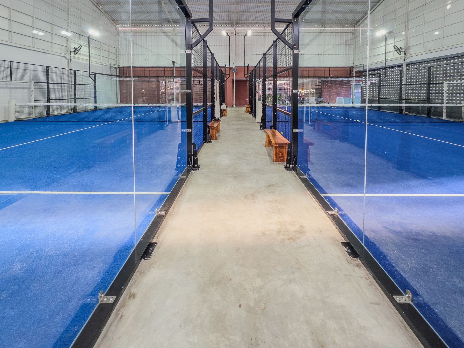 Moderne Indoor-Padel-Courts mit blauem Belag und Glaswänden